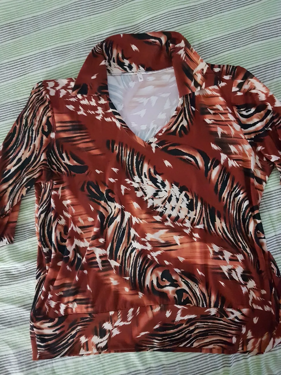 Remera manga 3/4 con estampa animal print en tonos marrones y negros. Cuello en V con solapa.