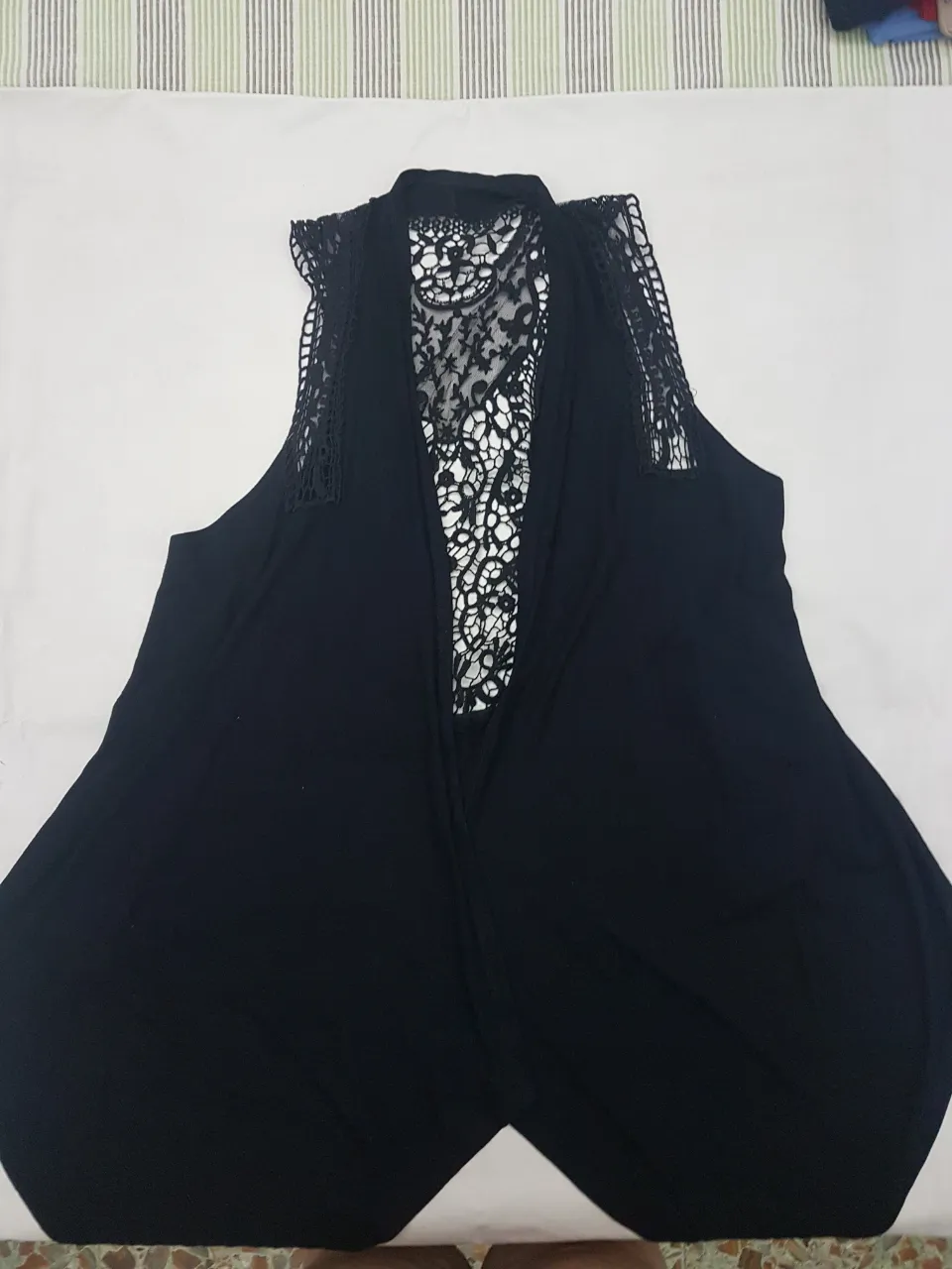 Chaleco negro con detalles de encaje en la espalda y hombros. Diseño abierto y moderno, ideal para complementar cualquier outfit.
