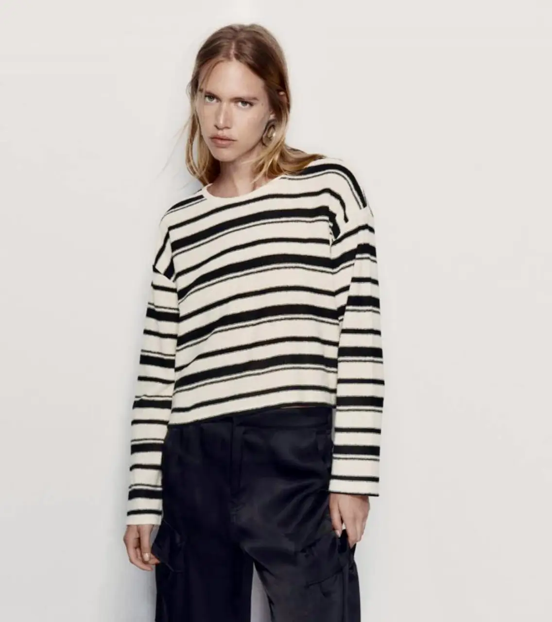 Sweater a rayas blanco y negro, de corte crop y manga larga. Ideal para un look casual y moderno.