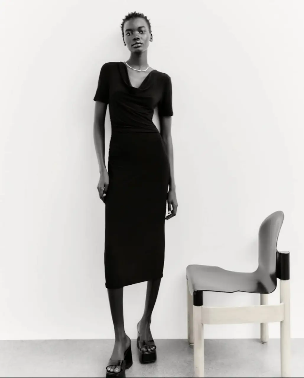 Vestido midi negro con cuello drapeado y mangas cortas. Ideal para un look elegante y versátil.