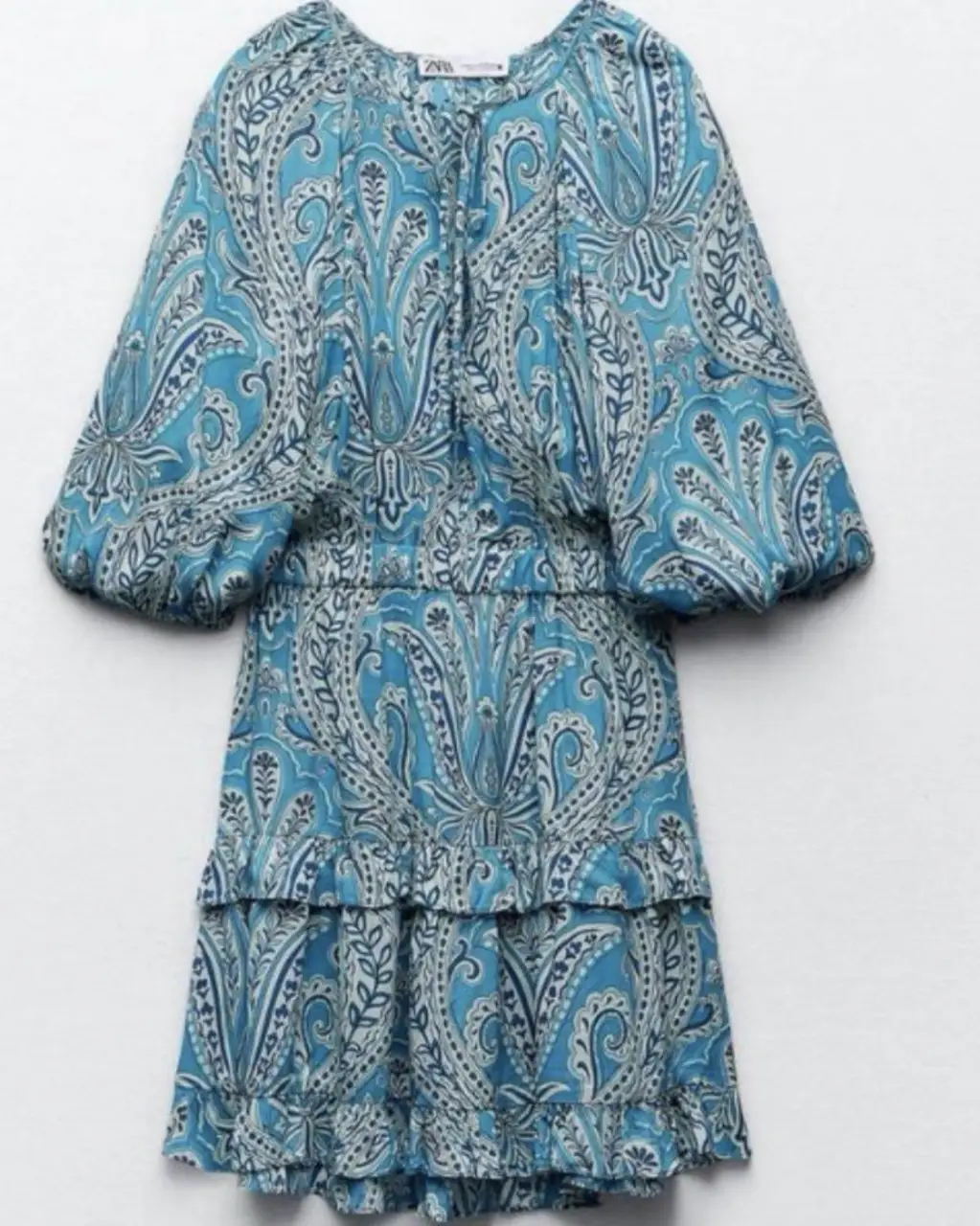 Vestido midi con estampado paisley en tonos celeste y blanco. Diseño con mangas globo y volados en la falda, ideal para un look bohemio y fresco.