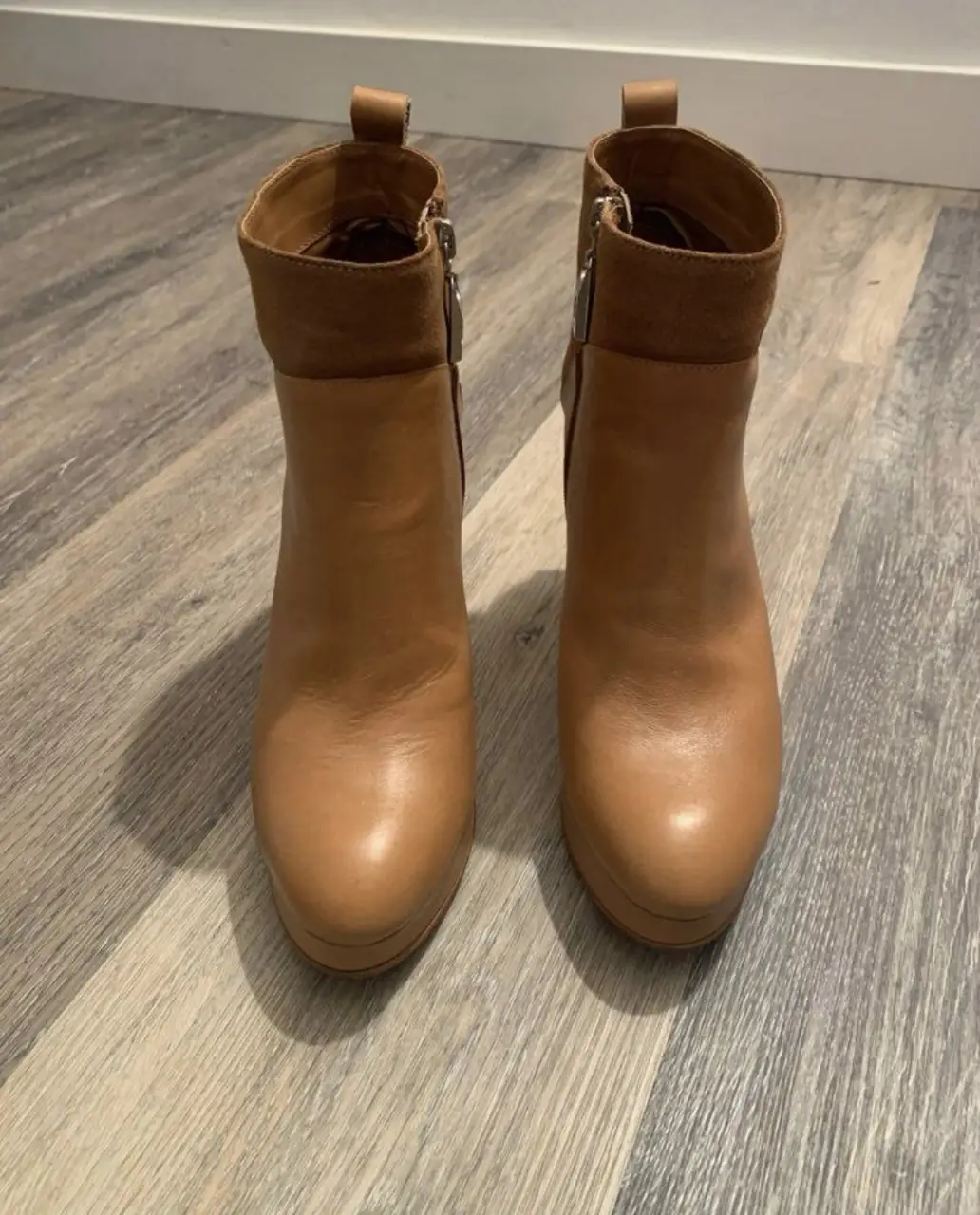 Botines de cuero color marrón claro con taco alto y plataforma. Diseño elegante con detalles de gamuza en la parte superior. Cierre lateral para facilitar el calce.