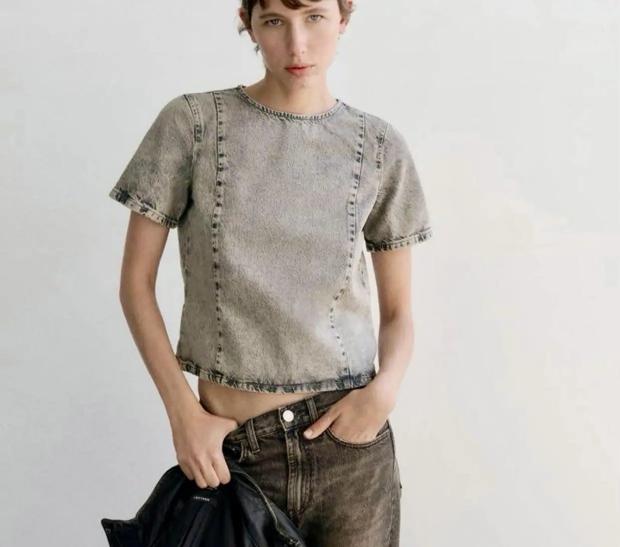 Remera de jean gris con mangas cortas y detalles de costura. Corte cropped y cierre con botones en la espalda. Ideal para un look casual y moderno.