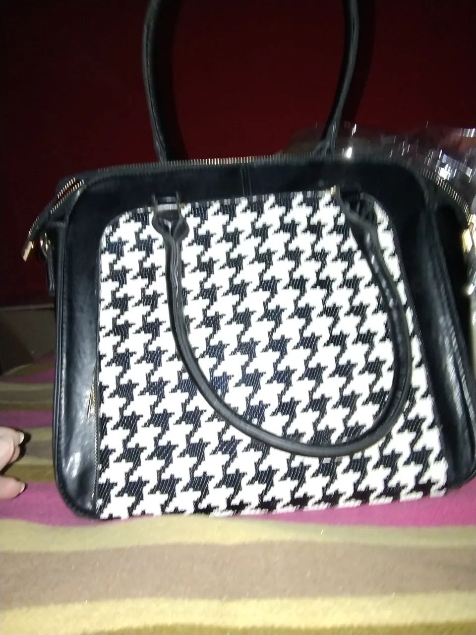 Cartera de mano para mujer, con diseño de pata de gallo en blanco y negro. Posee manijas cortas y cierre superior. Interior con bolsillo.
