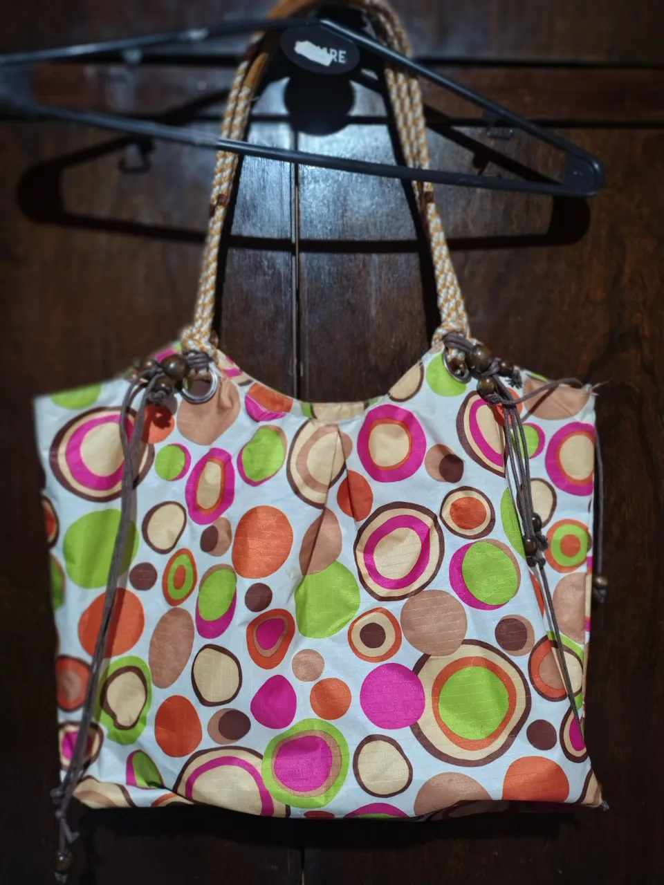 Bolso de playa con estampado de círculos en tonos naranja, rosa, verde y marrón. Ideal para llevar todo lo necesario con estilo y color.
