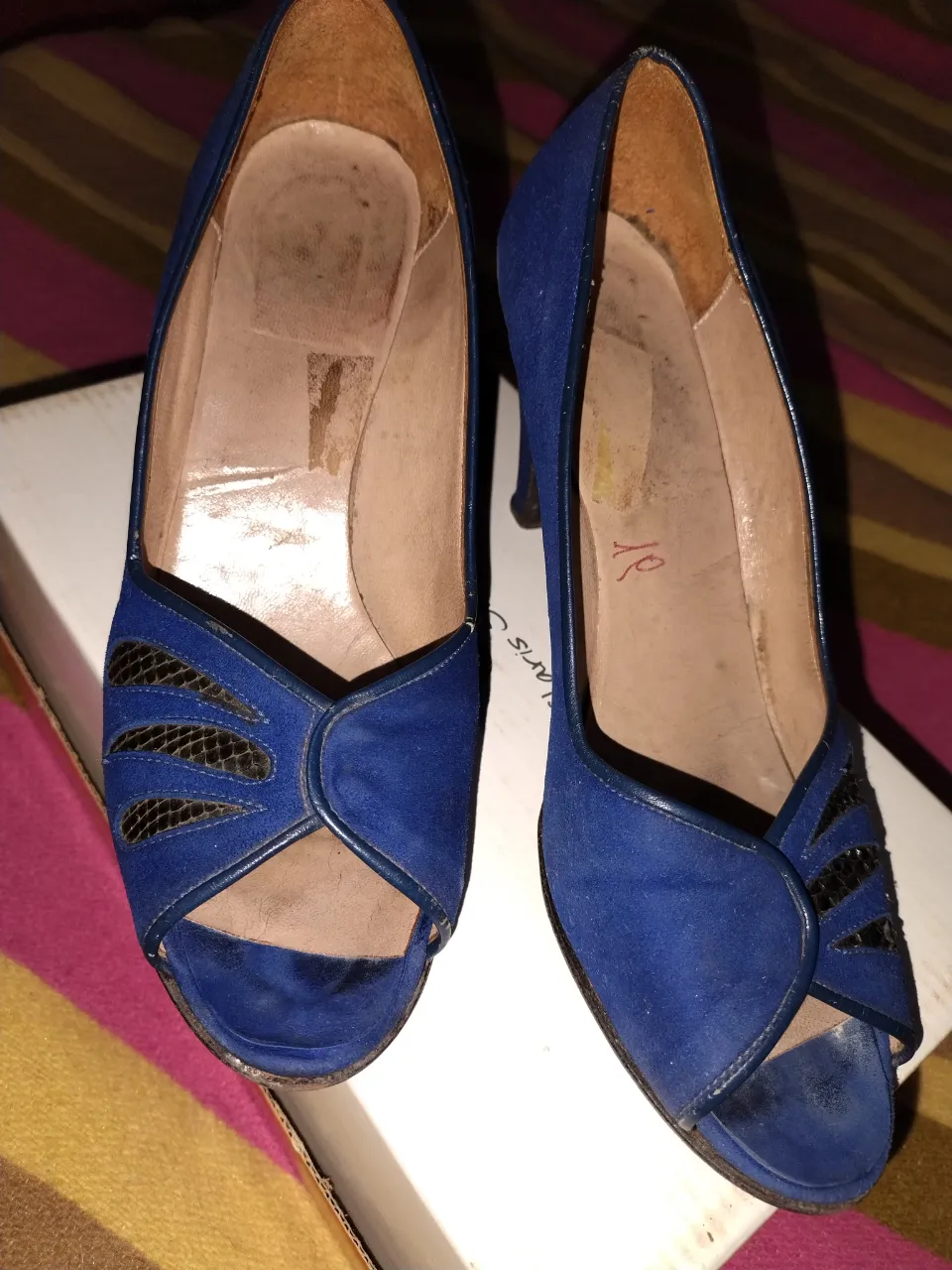 Sandalias azules de gamuza con detalles en negro. Diseño vintage con taco alto y puntera abierta. Ideales para un look elegante y retro.