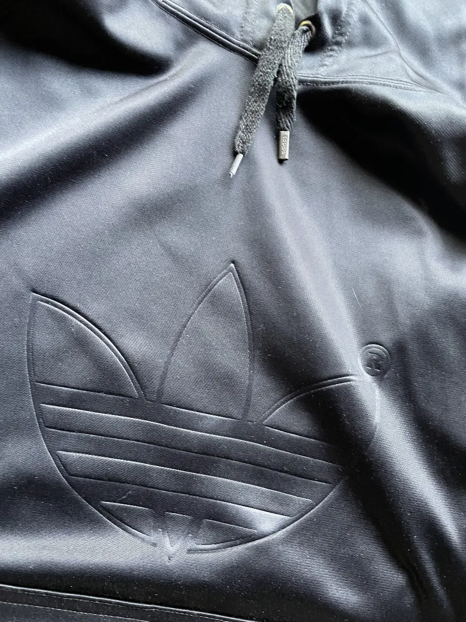 Buzo Adidas negro con capucha y el logo icónico en relieve. Ideal para un look deportivo y casual.