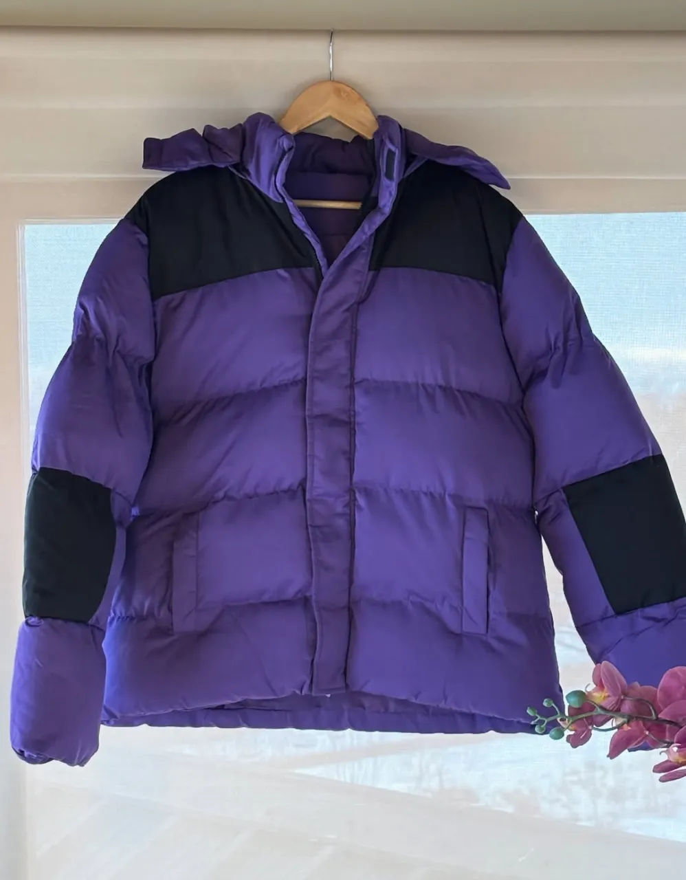 Campera puffer de abrigo para mujer, color violeta con detalles en negro. Ideal para el invierno, con capucha y bolsillos.