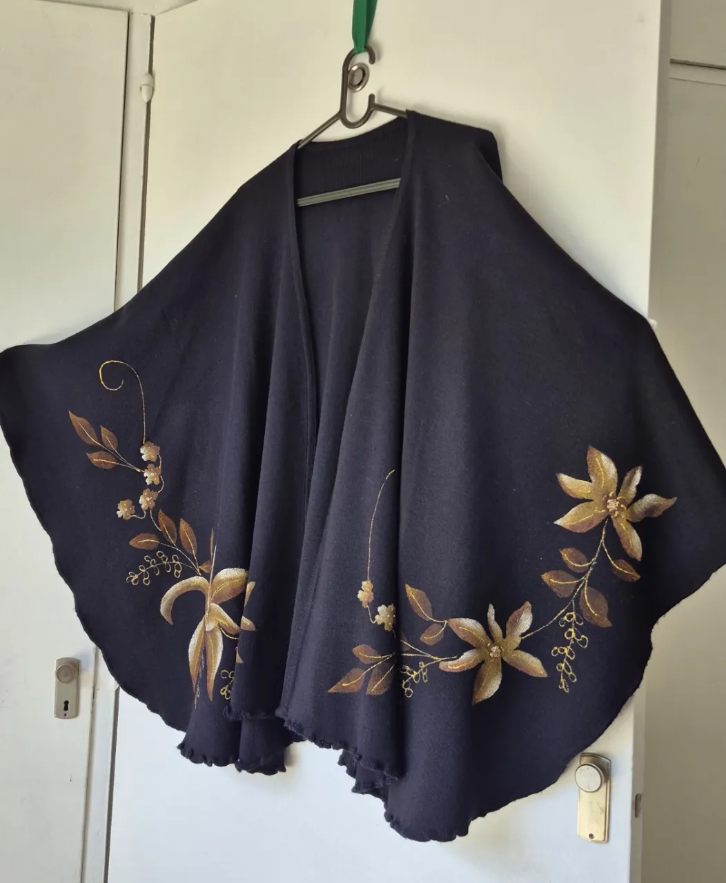 Poncho ruana  tejido negro con delicados detalles florales pintados a mano en tonos dorados y marrones. Un diseño único y elegante, perfecto para añadir un toque especial a cualquier atuendo.