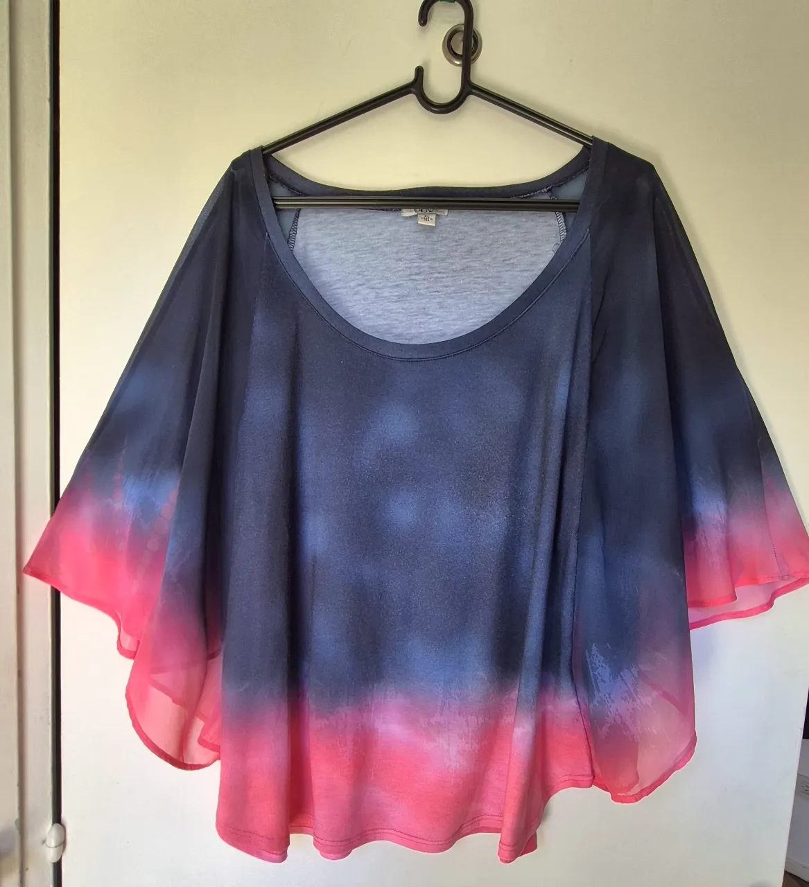 Remera estilo poncho con mangas amplias y degradé de color azul a rosa vibrante. Ideal para un look casual y moderno.