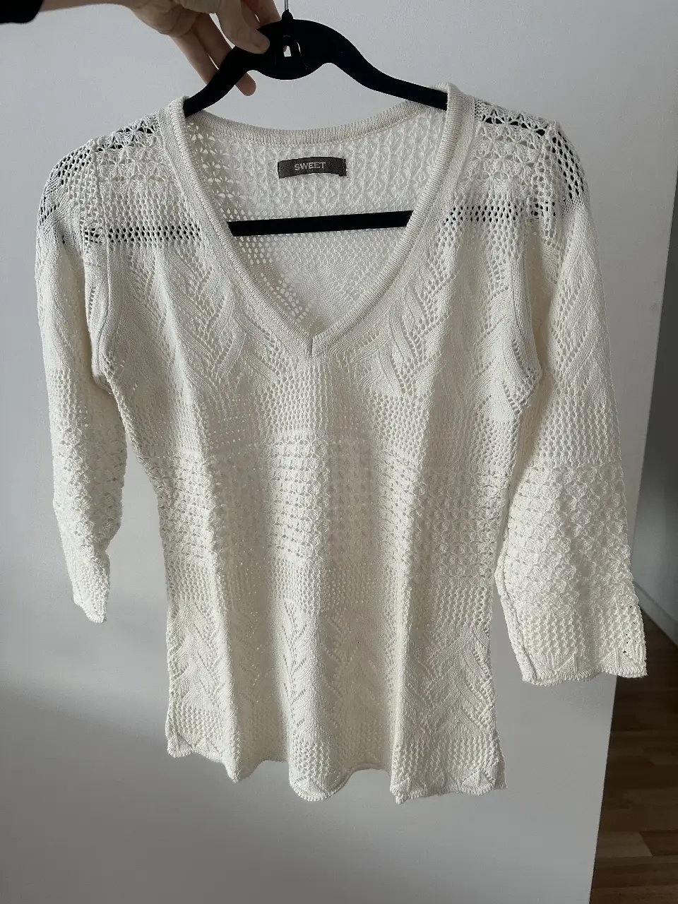 Sweater calado de mujer de color crudo, con escote en V y mangas 3/4. Tejido calado con detalles en relieve. Ideal para un look casual y fresco.