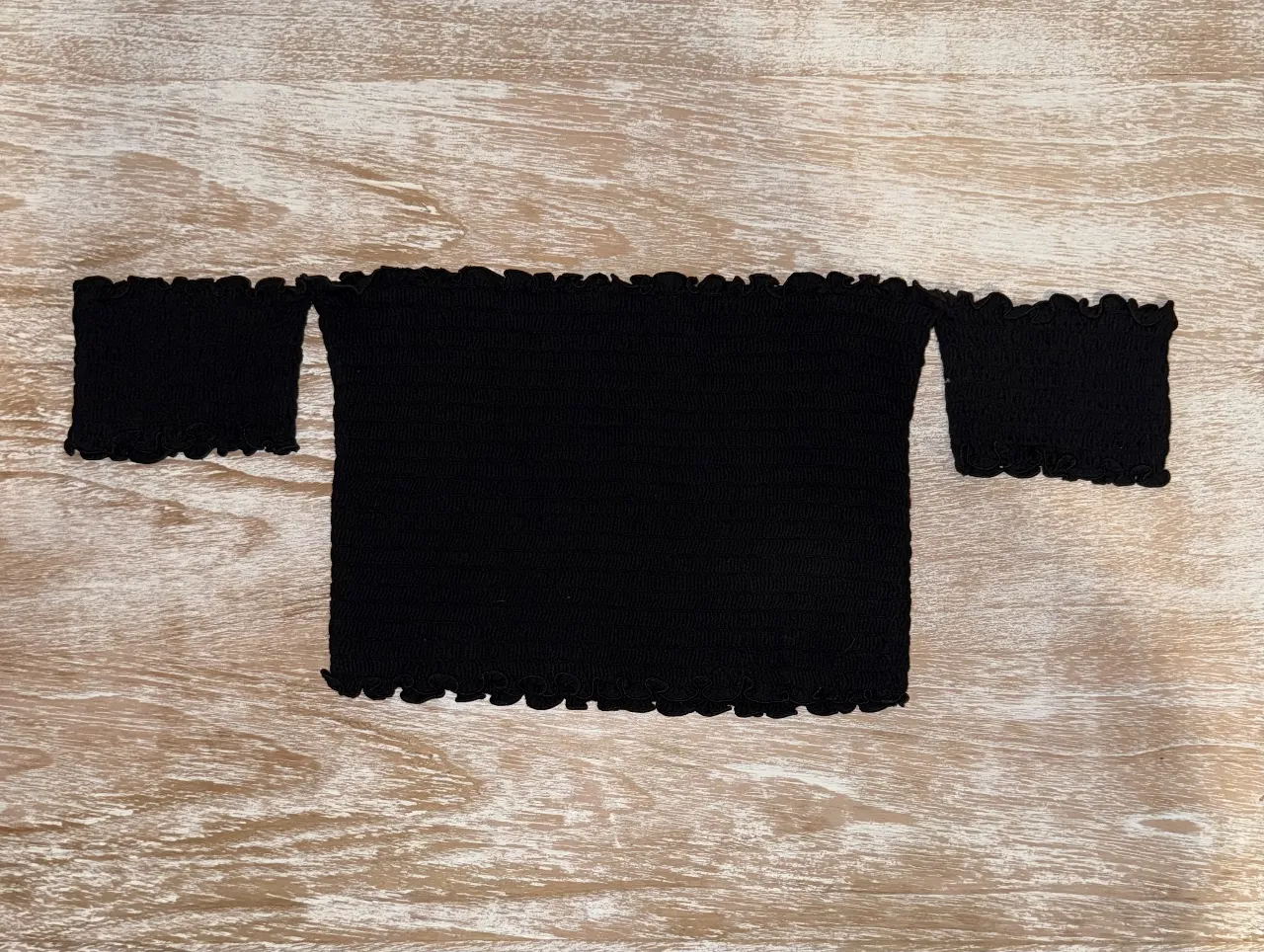 Top strapless negro con diseño de volados en los bordes y mangas cortas. Ideal para un look moderno y versátil. Es S pero al ser elastizado, puede servir para varios tipos de cuerpo.