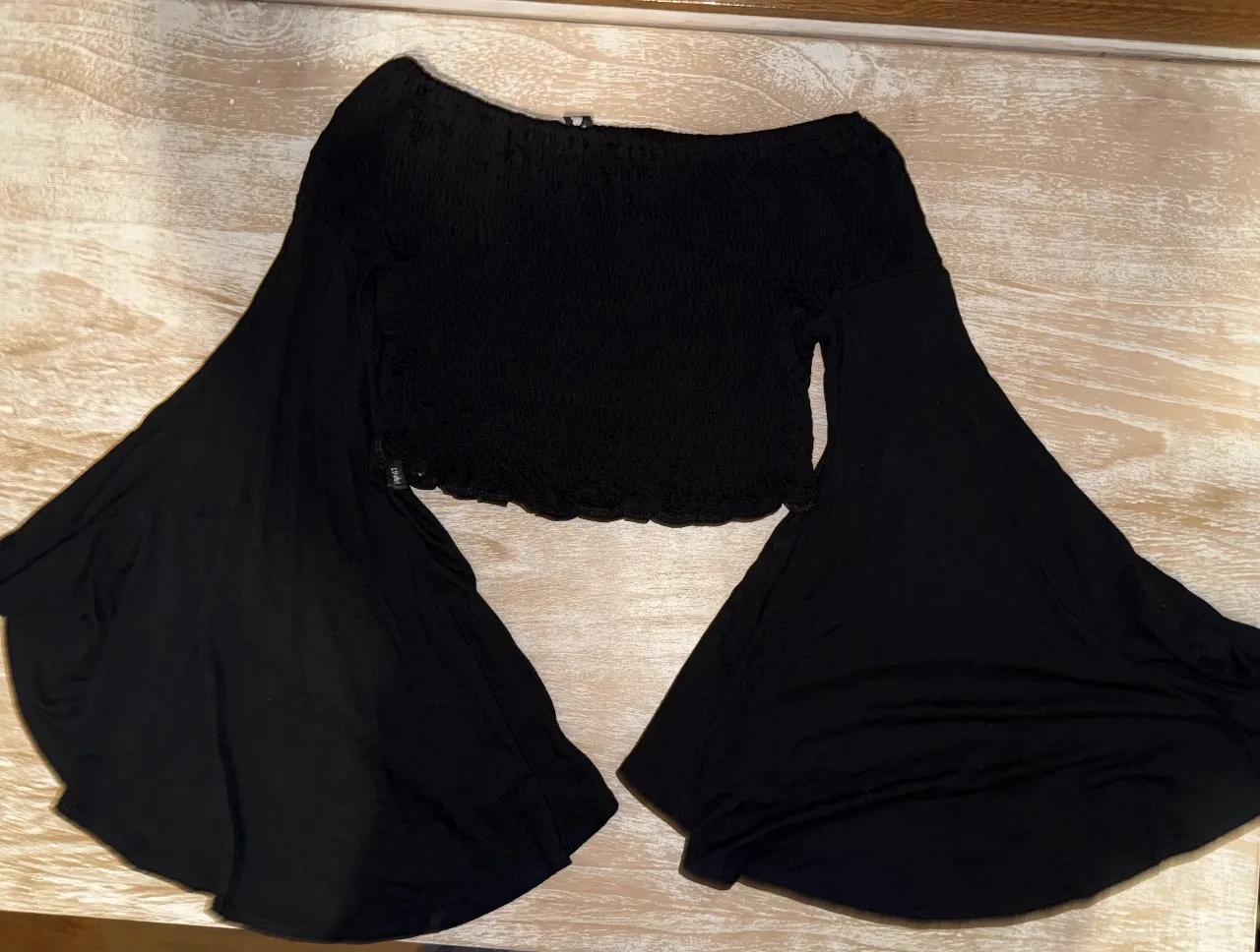 Top negro con mangas acampanadas, ideal para un look moderno y elegante. Perfecto para salir o para un evento especial.