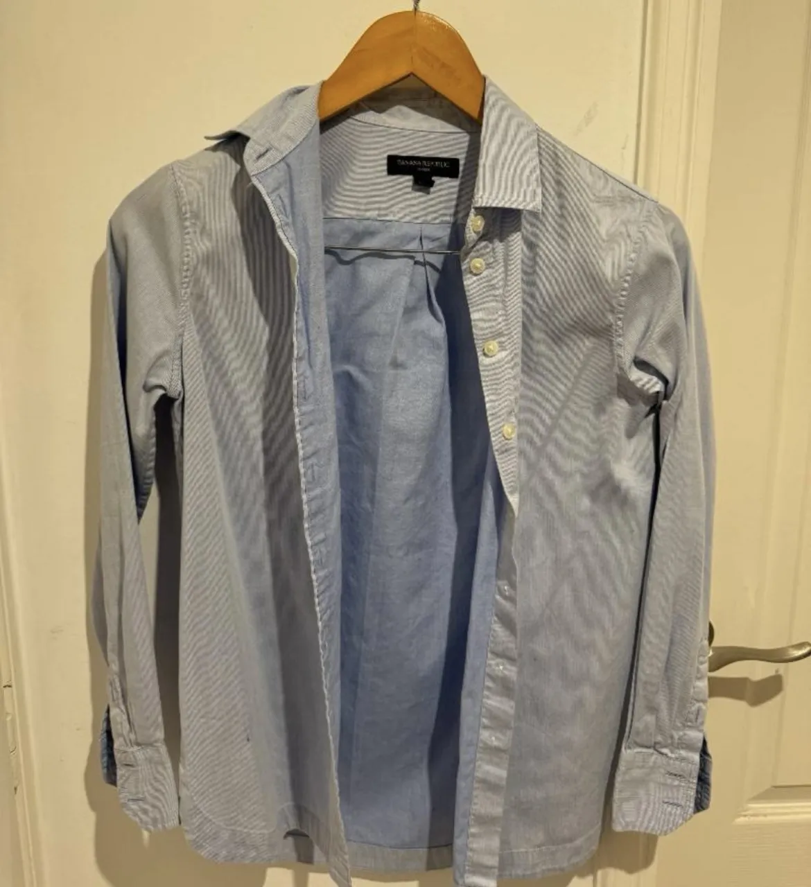 Camisa de manga larga a rayas finas celestes y blancas. Posee botones al frente y en los puños.