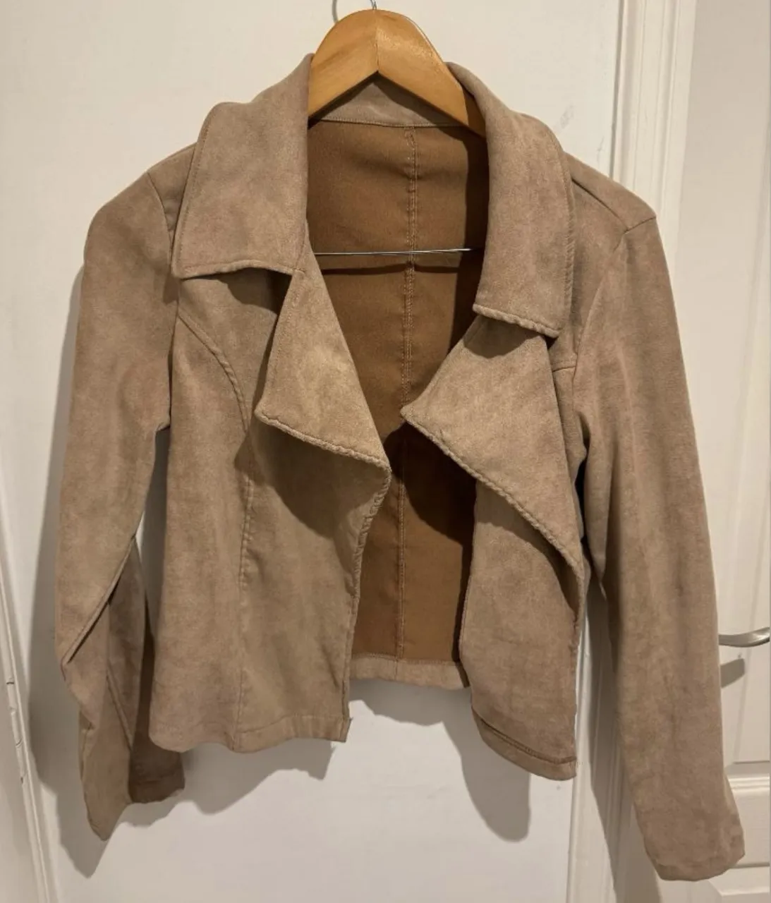 Campera corta de gamuza sintética color beige. Tiene cuello solapa y mangas largas