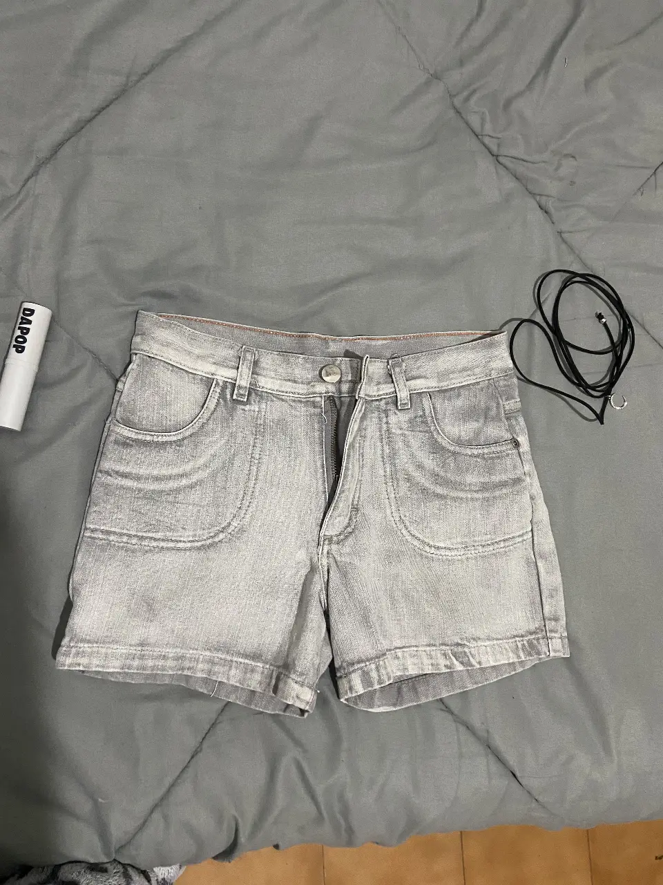 Short de jean gris claro, tiro medio, con bolsillos delanteros y traseros. Ideal para un look casual y cómodo.