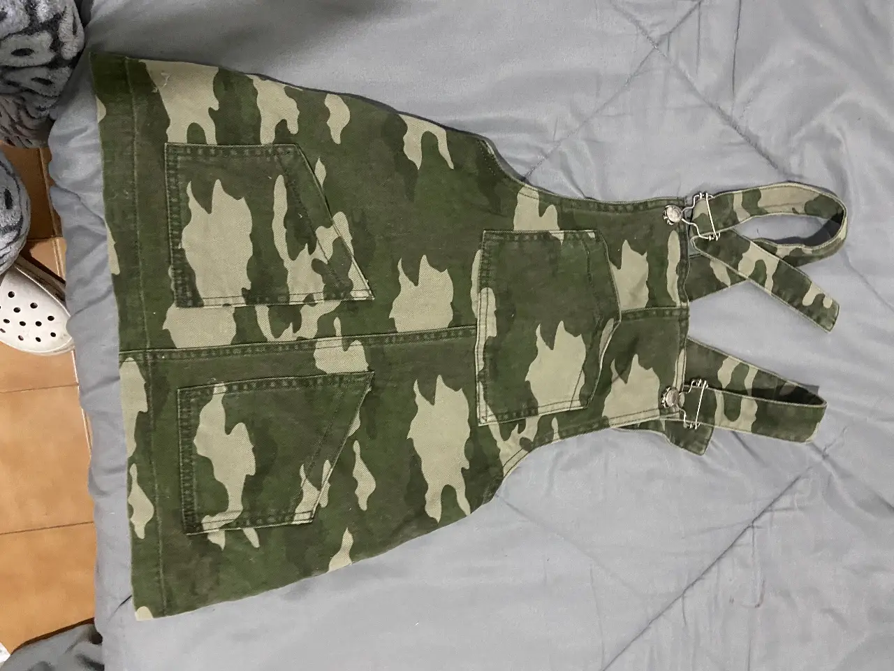 Vestido jardinero de jean con estampado camuflado. Posee bolsillos delanteros y traseros, y tirantes ajustables. Ideal para un look casual y moderno.