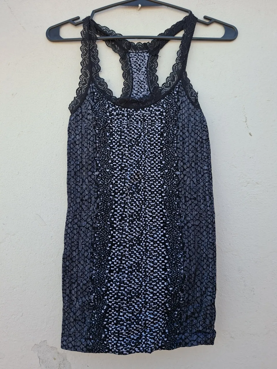 Musculosa estampada con detalles de encaje negro en breteles y escote. Ideal para un look canchero y cómodo.