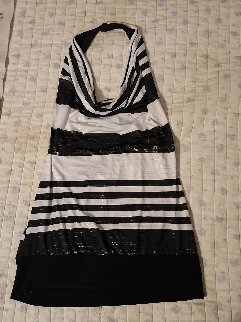 Vestido corto a rayas blancas y negras, con escote halter y detalles brillantes. Ideal para salidas nocturnas o fiestas.