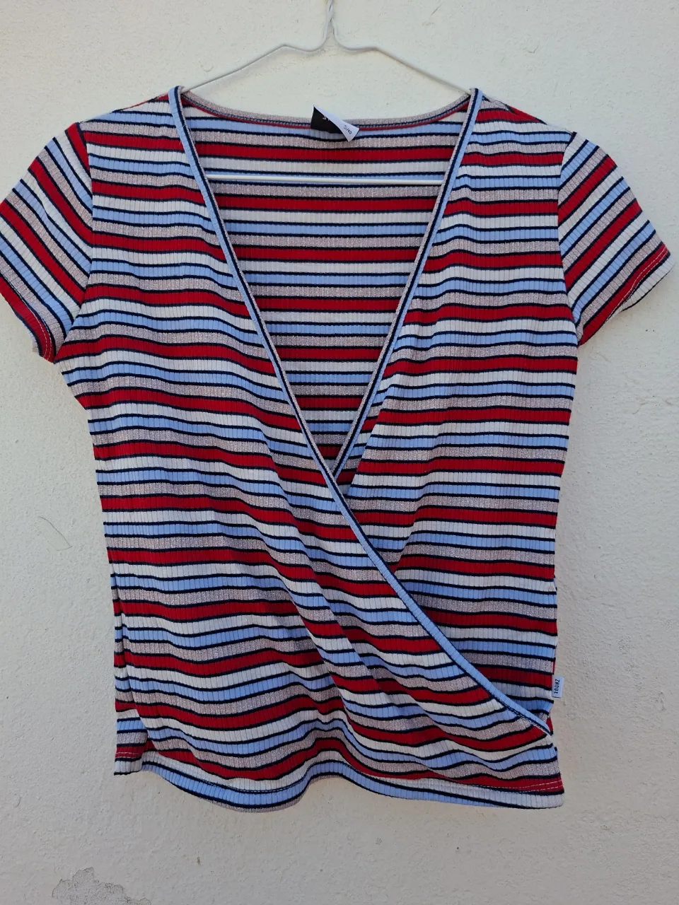 Remera a rayas súper canchera, con escote cruzado y detalles plateados que le dan un toque especial. Ideal para un look moderno y divertido.