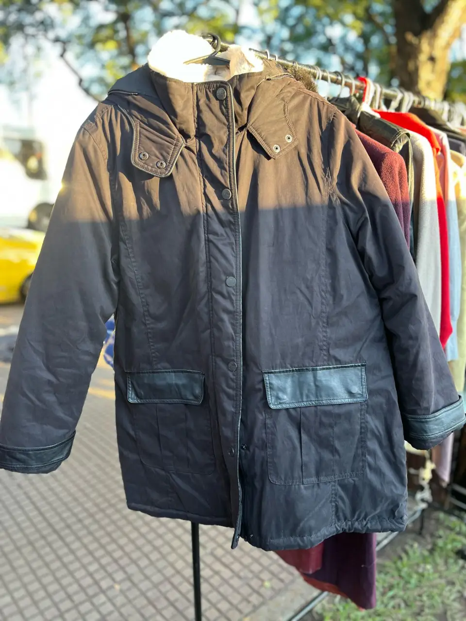Campera negra con capucha y detalles en cuero sintético en los bolsillos. Ideal para el invierno, con forro interior de piel sintética en la capucha.