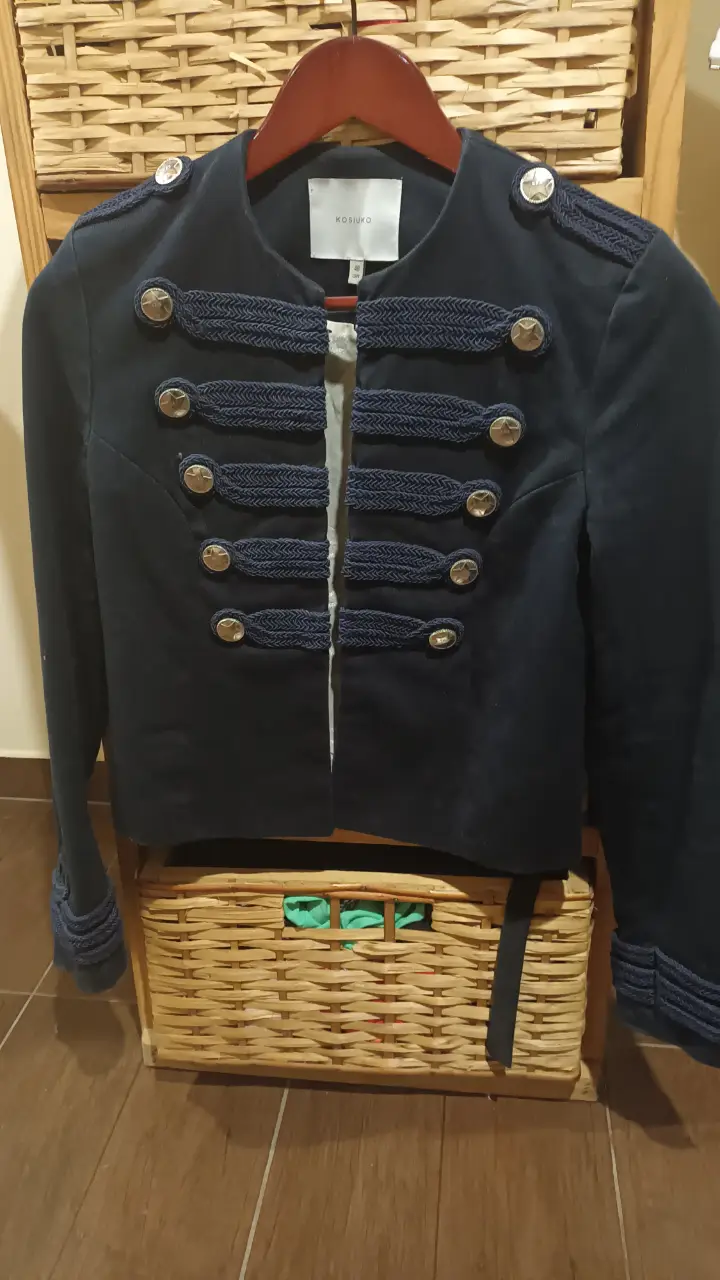 Chaqueta blazer azul marino de la marca KOSIUKO, con detalles militares. Posee botones dorados y detalles en los hombros y puños. Ideal para un look elegante y sofisticado.