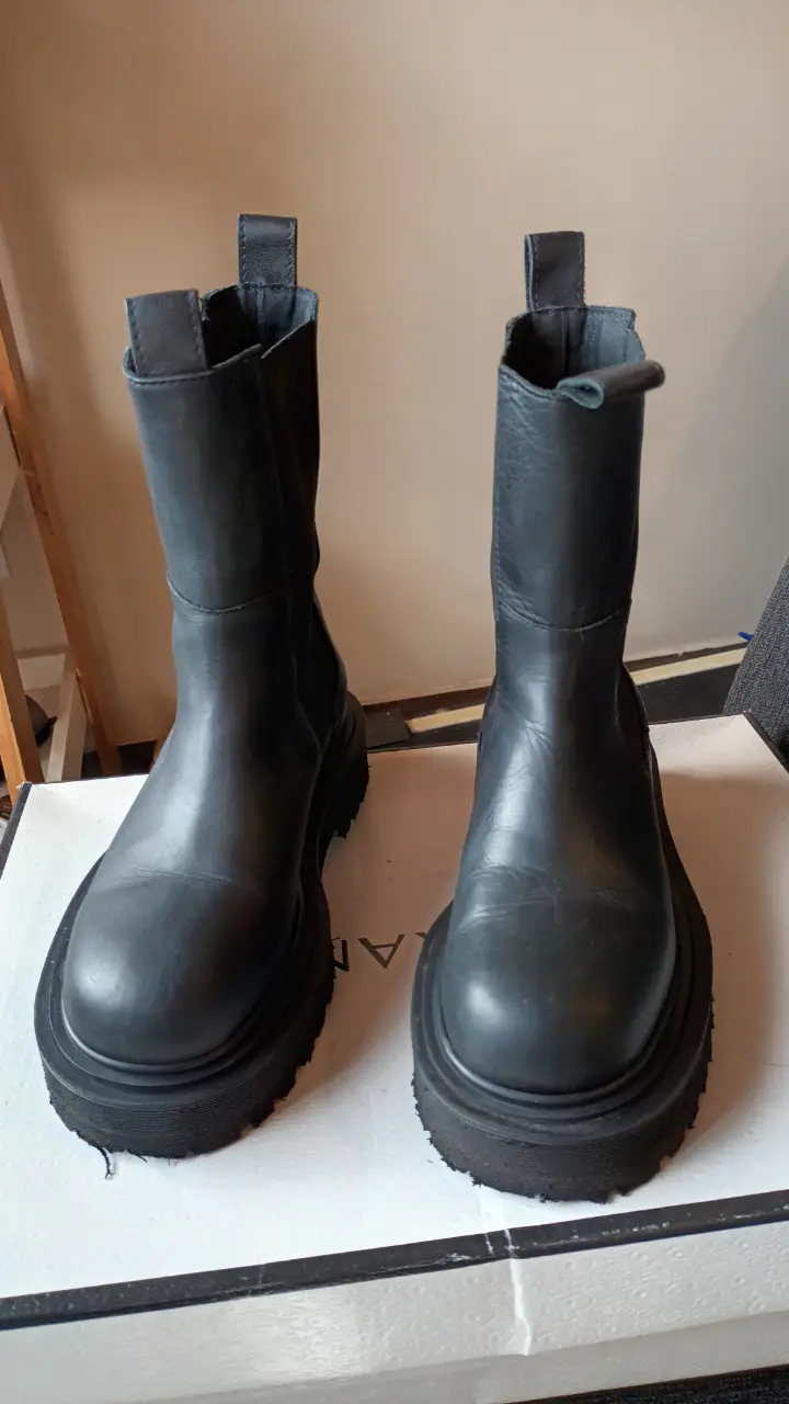 Botas negras de cuero con suela gruesa y detalle de la marca Sarkany en la caña. Ideales para un look moderno y urbano.