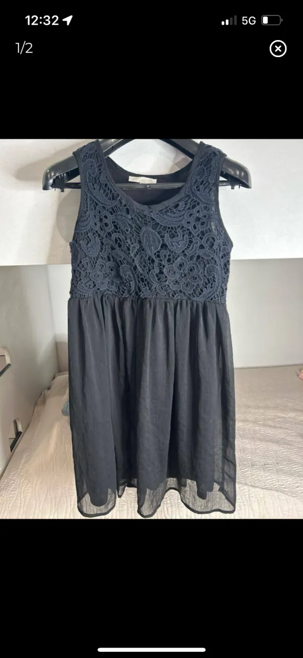 Vestido negro corto con detalles de encaje en la parte superior y falda plisada. Ideal para eventos o salidas.