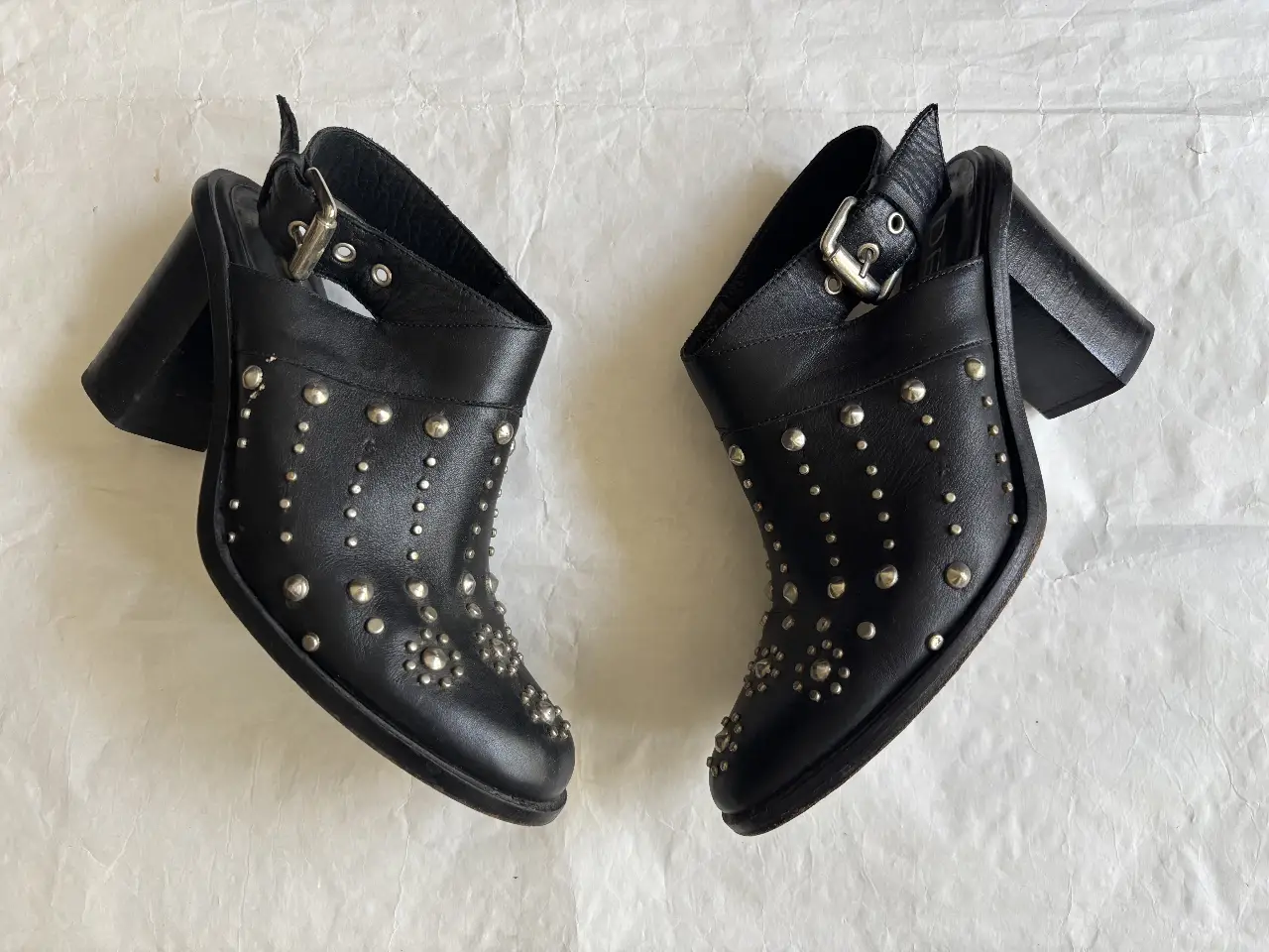 Zuecos negros de cuero  DE LA OSTIA con tachas plateadas. Diseño con hebilla en el tobillo y taco ancho. Ideales para un look rocker y canchero. UNA puesta REAL. 