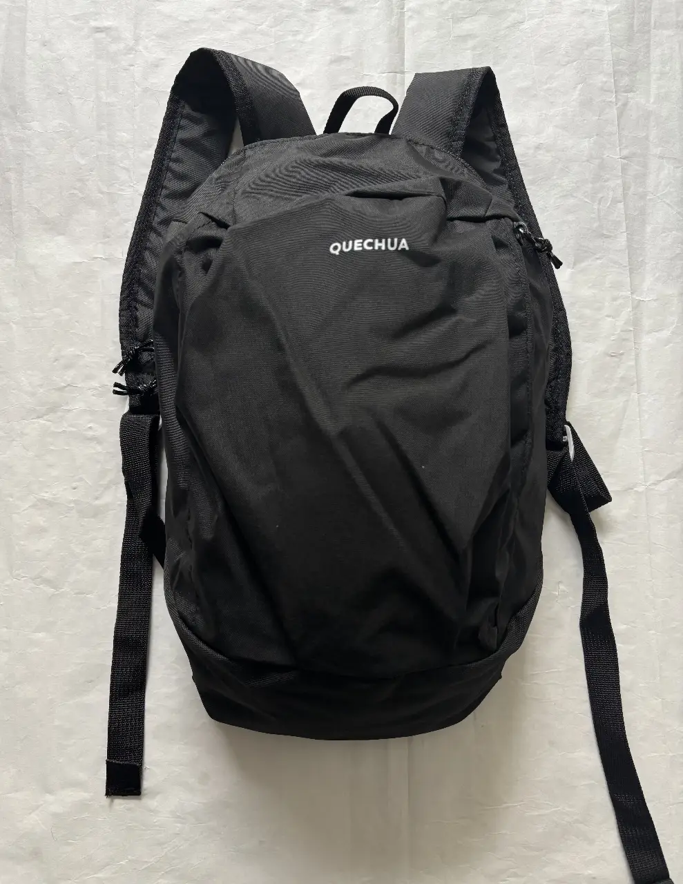 Mochila Quechua negra 10 lts, ideal para actividades al aire libre. Cuenta con un compartimento principal amplio y un bolsillo frontal con cierre. Perfecta para llevar tus esenciales.
