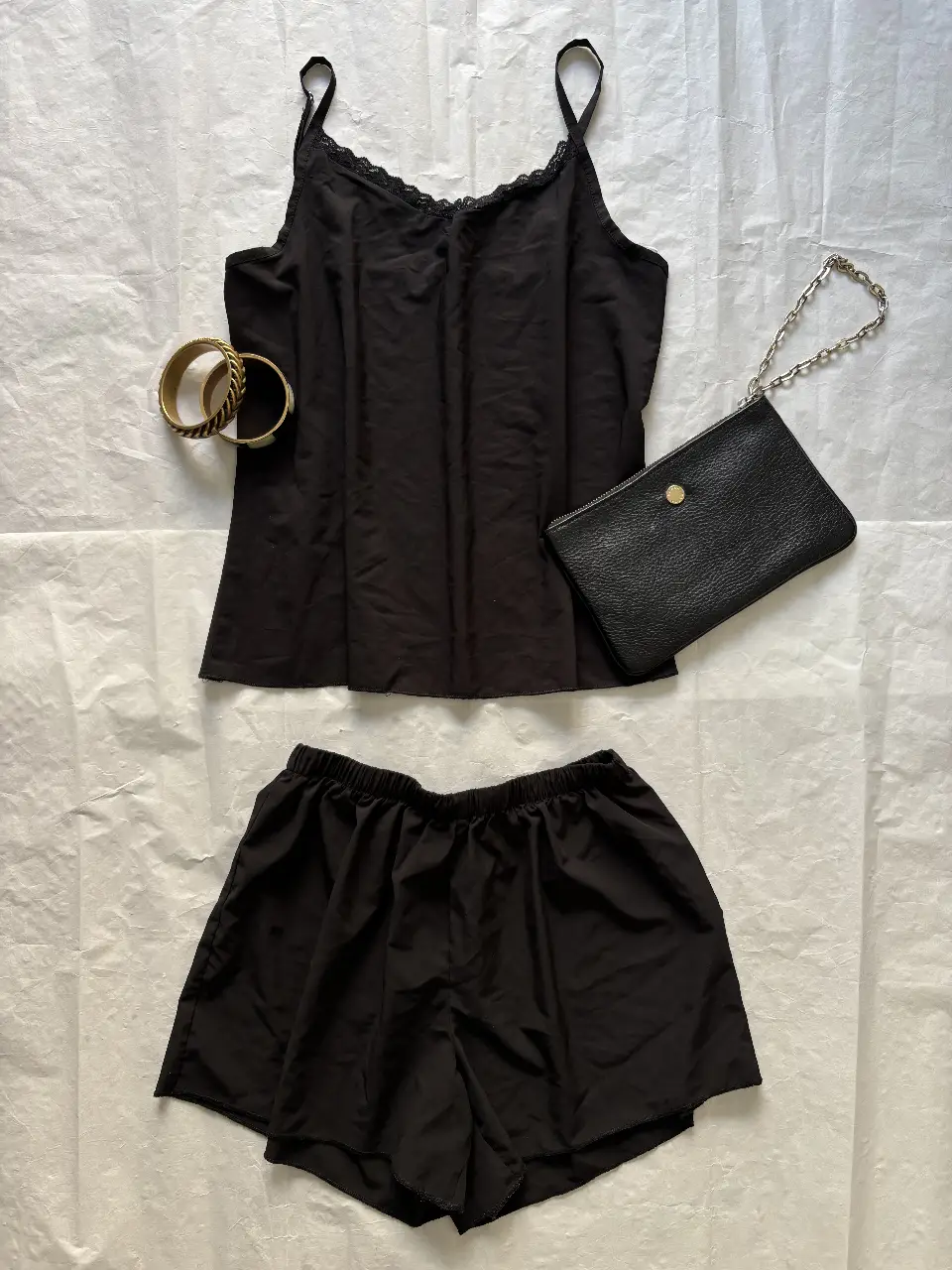 Pijama seda sintética de dos piezas en color negro. Incluye un top con tirantes finos y detalles de encaje en el escote, y un short con cintura elástica. NUEVO talle S.