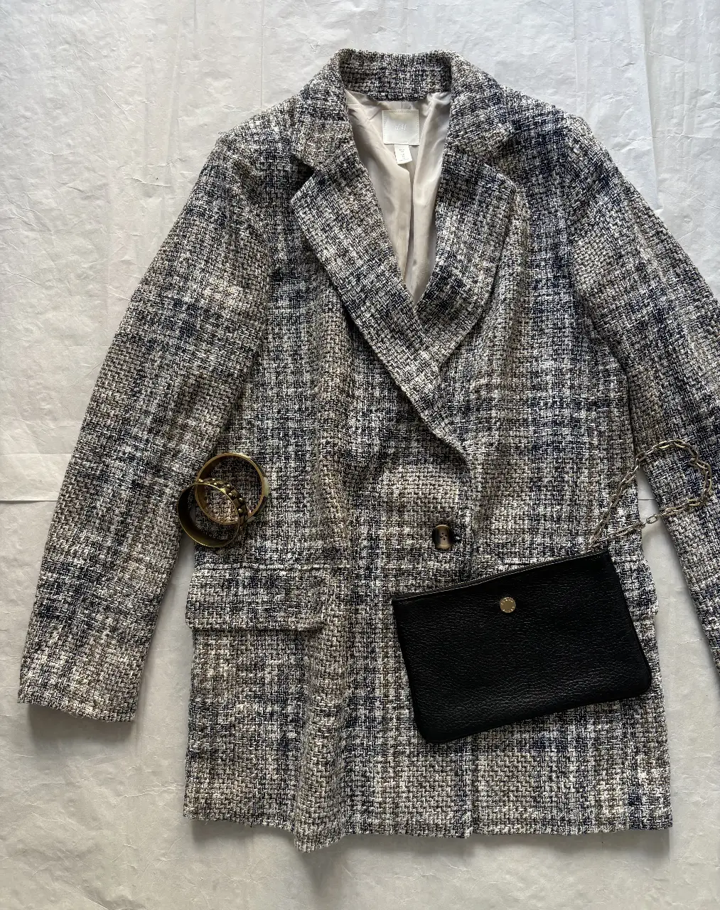 Elegante blazer de tweed en tonos grises y blancos, ideal para un look sofisticado. Confeccionado con un tejido texturizado, este blazer es perfecto para combinar con diferentes outfits. Incluye detalles como bolsillos y botones.