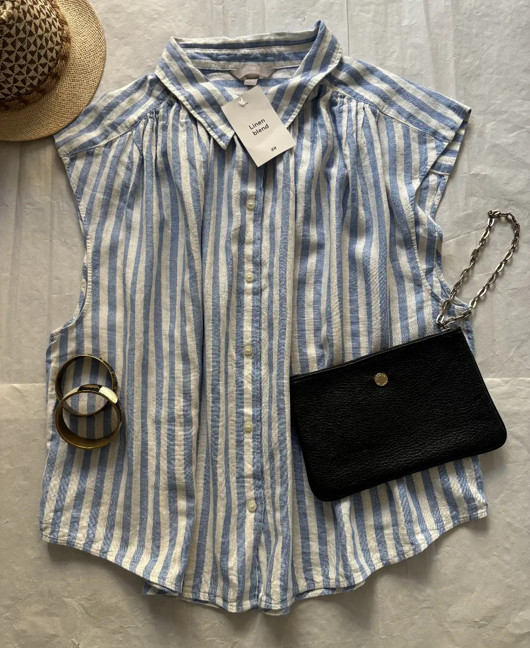 Blusa de lino a rayas celeste y blanco, con cuello camisero y mangas cortas. Ideal para un look fresco y casual.