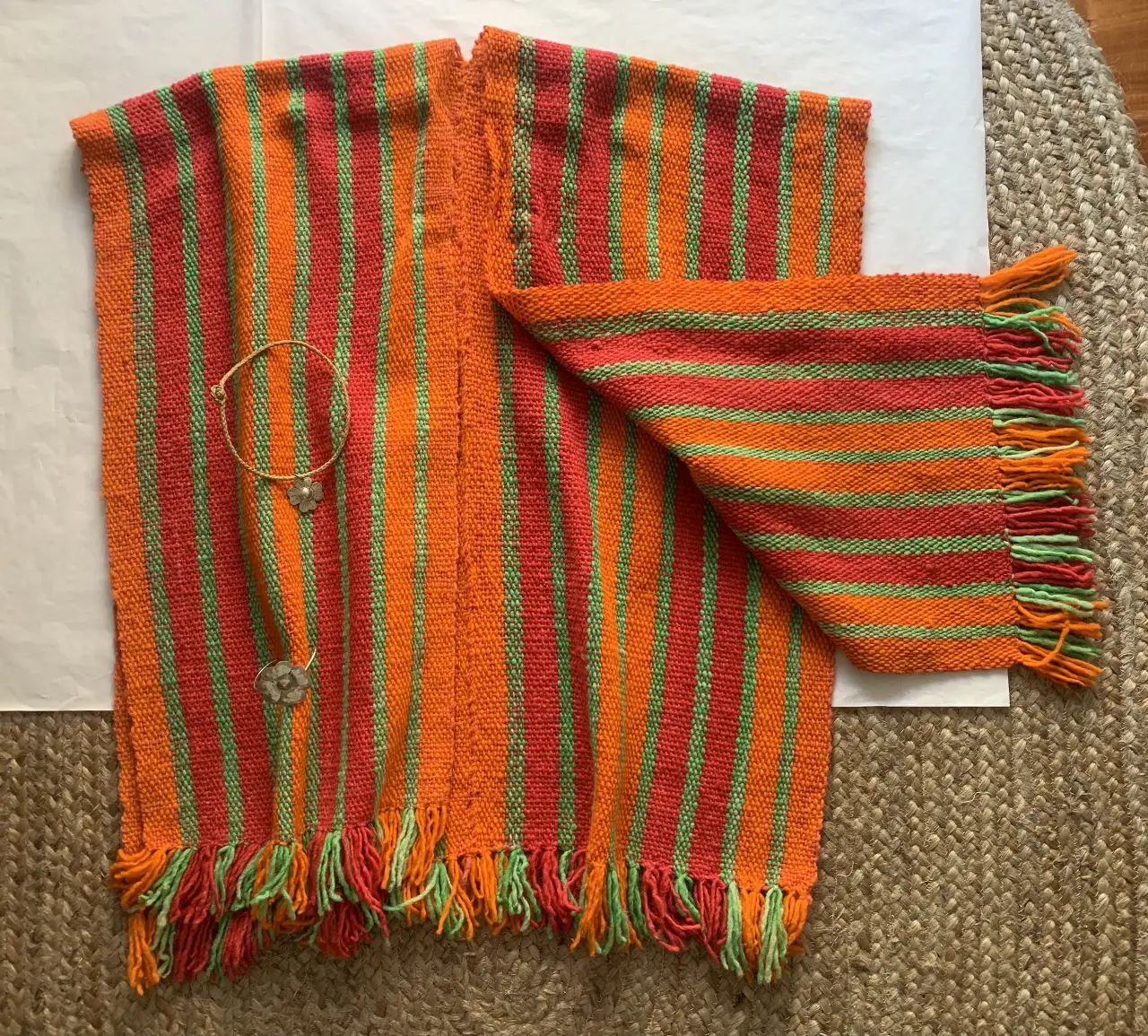 Ruana artesanal tipo poncho con diseño a rayas en tonos naranja, rojo y verde. Traido del norte, lana pura de ove ja. 