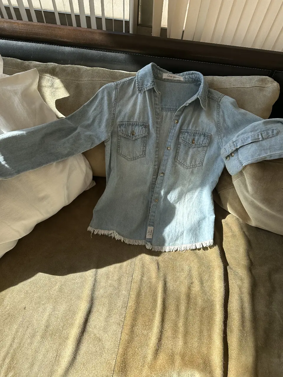 Camisa de jean celeste con flecos en el borde inferior. Ideal para un look casual y moderno. Perfecta para combinar con jeans o pantalones de vestir.