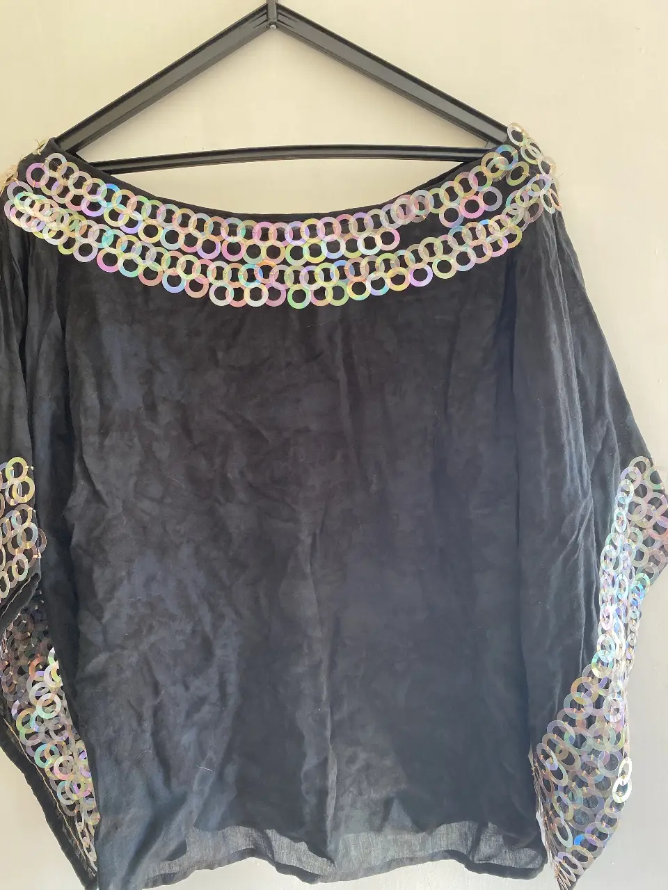 Blusa negra con detalles de lentejuelas en cuello y mangas. Ideal para eventos especiales o para darle un toque glam a tu look.