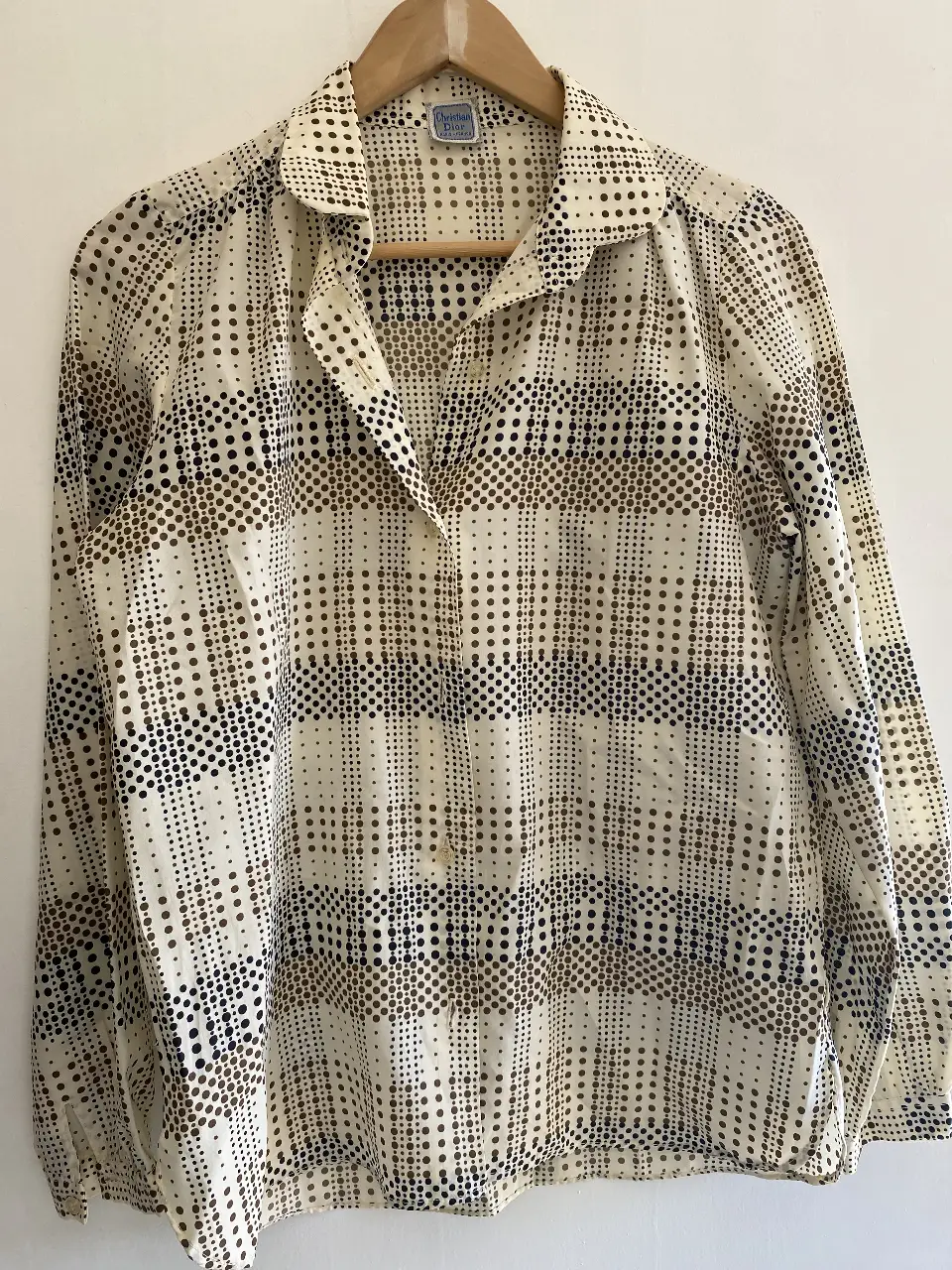 Blusa vintage de Christian Dior con estampado de lunares en tonos marrones y blancos. Corte clásico con cuello camisero y manga larga. Ideal para un look retro y elegante.