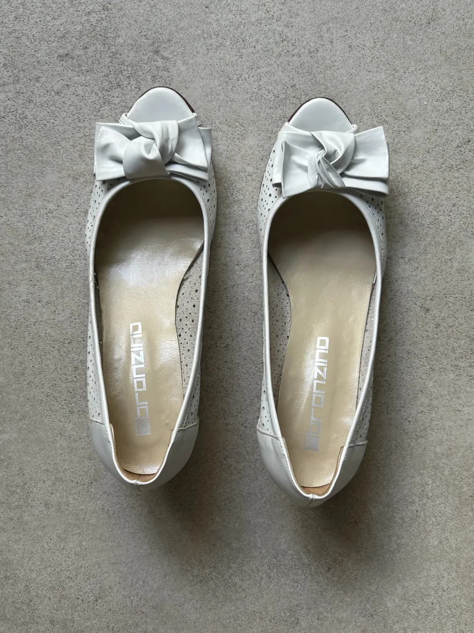 Zapatos blancos con lazo en la punta y detalles perforados. Tienen una cuña de madera.

Están impecables! ideal para Boda, fiesta, comunión 

Si bien su talle dice 38, tiene medidas de un 37.5.
Mide la plantilla aprox 23 cm
Horma chica