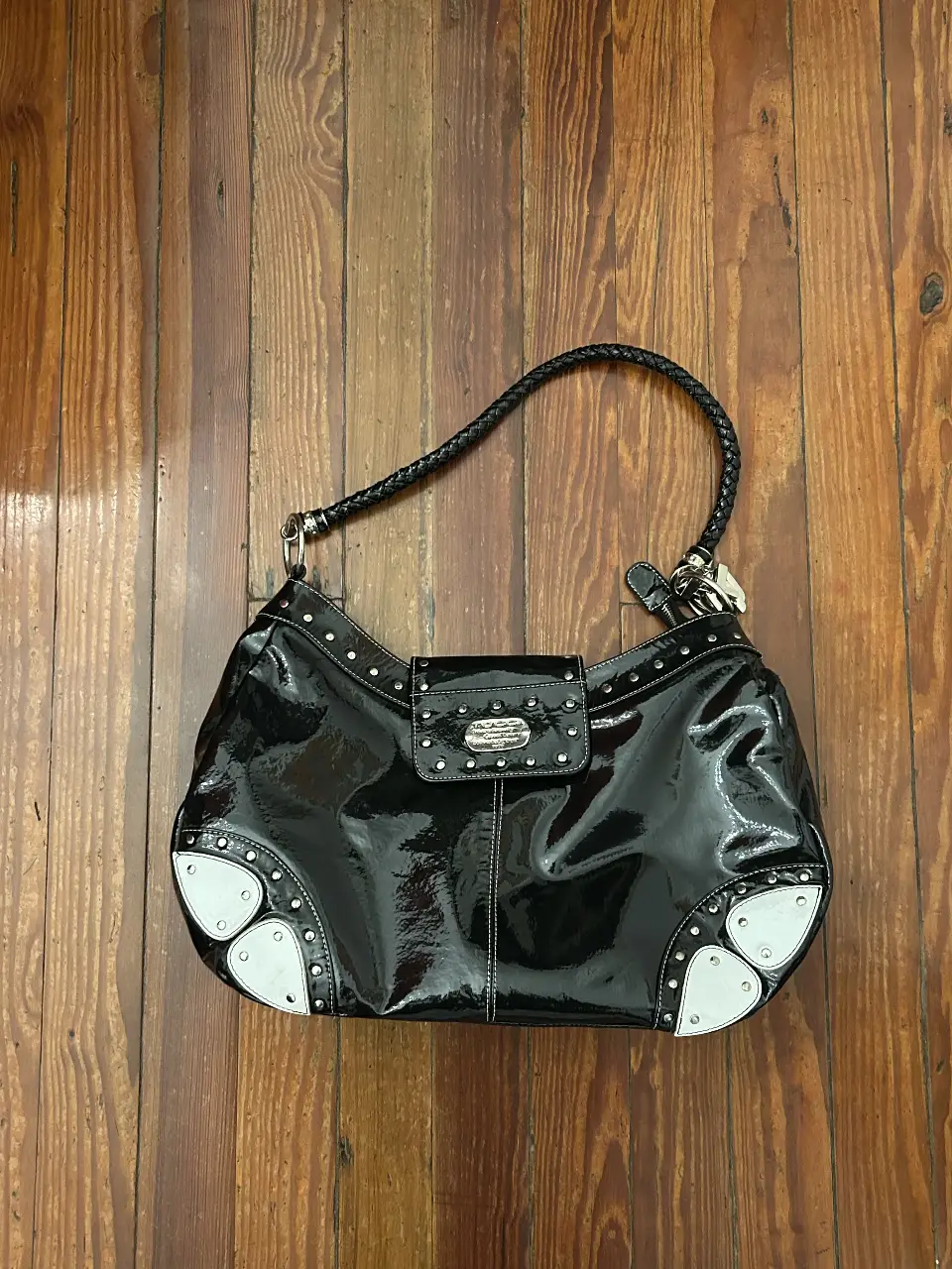 Cartera de hombro negra con detalles en blanco y tachas plateadas. tiene a modo de charm en el lateral las letras de la palabra “tucci”. medidas de la cartera: ancho 40 cm alto 28 cm base 11 cm
