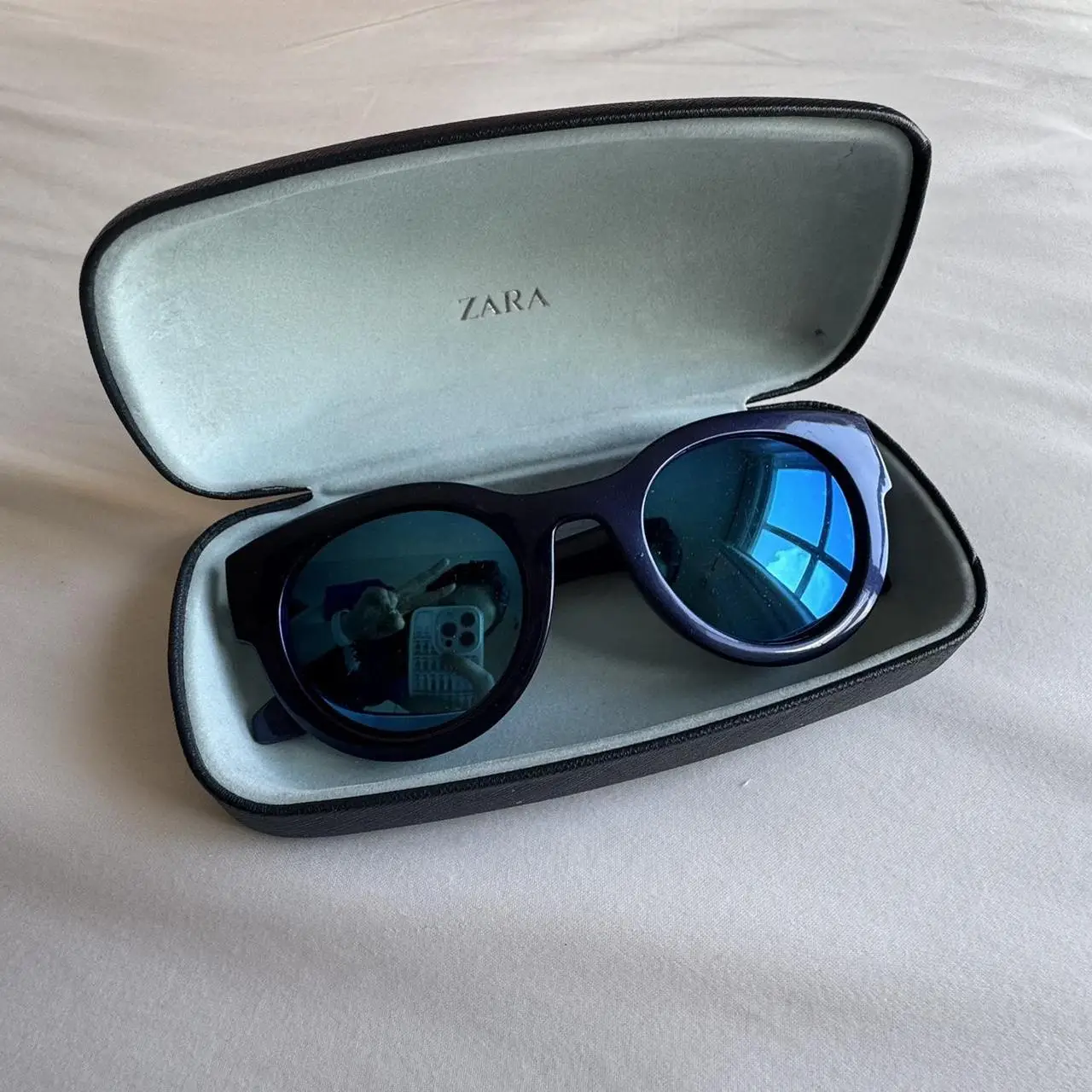 Anteojos de sol Zara, con marco azul y cristales espejados. Incluye estuche.