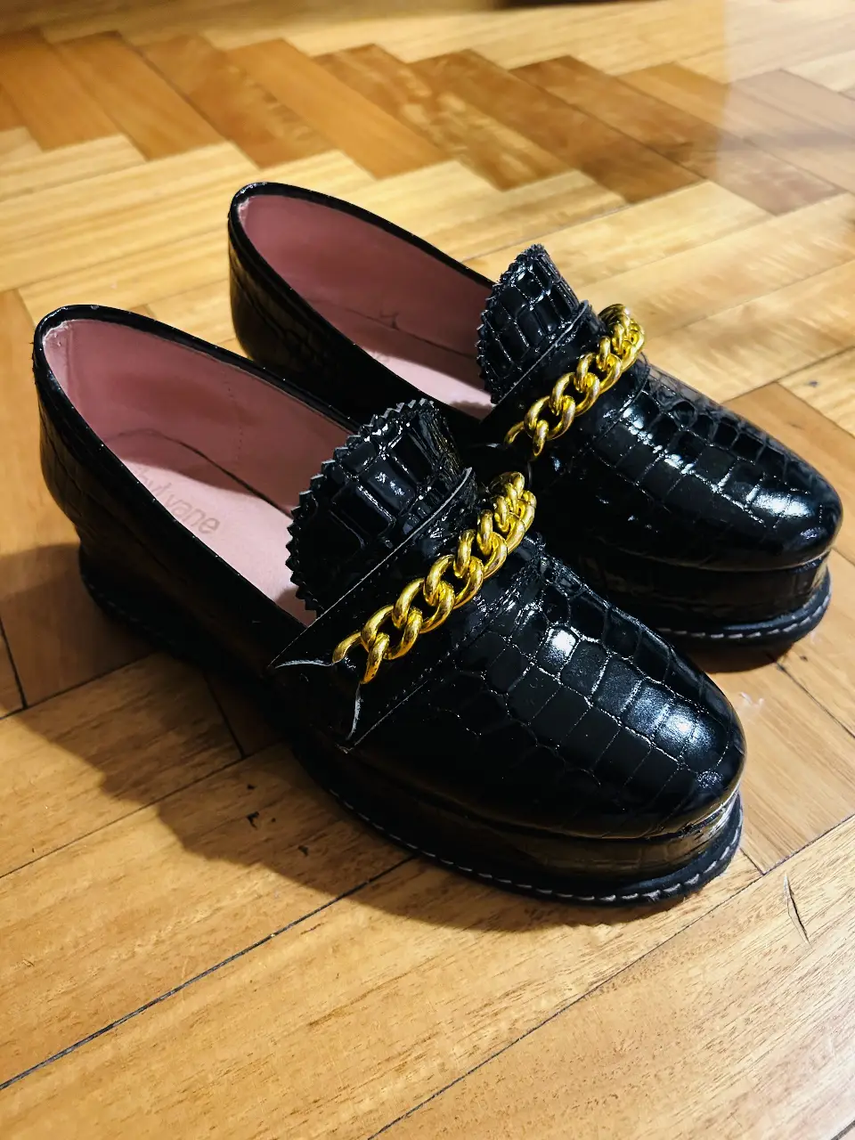 Mocasines negros de charol con detalle de cadena dorada. Un clásico renovado para un look elegante y moderno. 2 usos. impecables, material de croco-charol. con plataforma horma chica. 100% cuero. plantilla: 23 cm