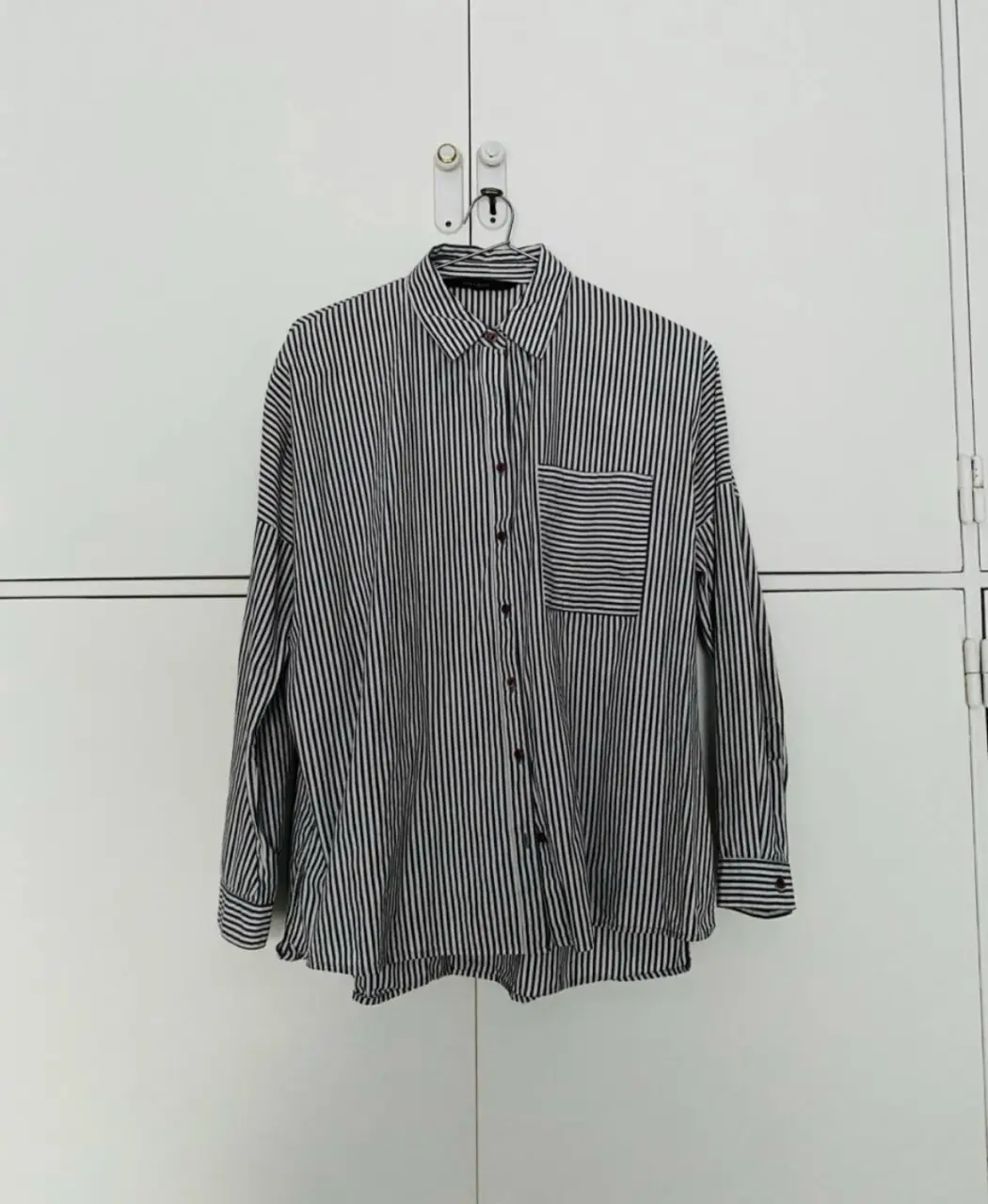 Camisa a rayas verticales en blanco y gris oscuro, de manga larga con bolsillo en el pecho. Marca Zara Basic, talle S. es holgada. medidas: hombro a hombro: 40 cm. / largo total: 65 cm / mangas: 56 cm aprox