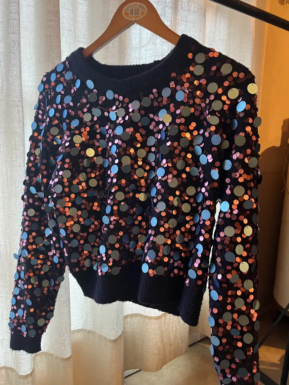 Sweater de punto azul marino con lentejuelas en tonos rosa, celeste y dorado. Ideal para darle un toque festivo a cualquier look.