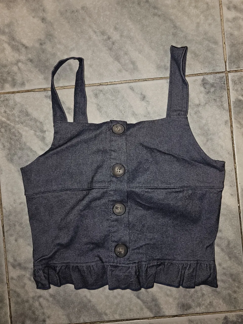 Top de jean azul con breteles y botones delanteros. Tiene volados en la parte inferior.elastizado
