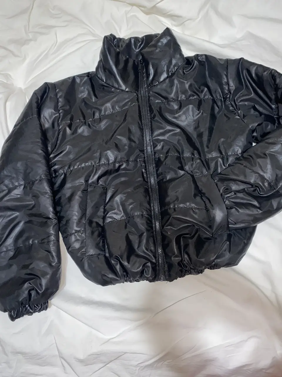 Campera puffer negra, ideal para el invierno. Confeccionada con material brillante y cierre frontal.