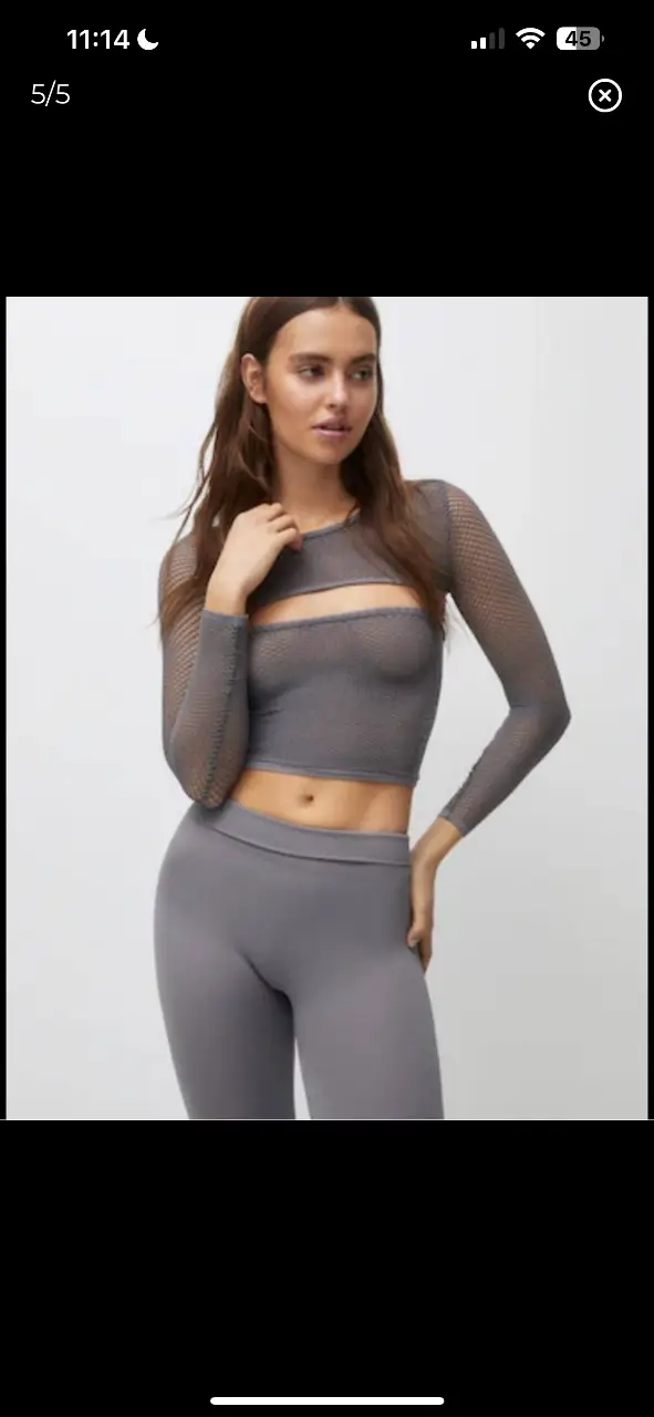 Top de red gris, con mangas largas y corte en el abdomen. Ideal para un look moderno y audaz.