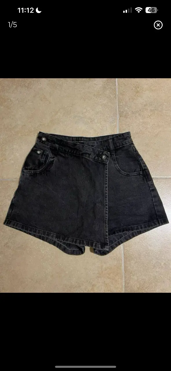 Short de jean negro con diseño envolvente y botones. Talle XS, ideal para un look casual y moderno.