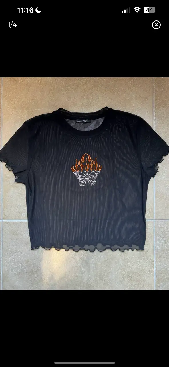Remera de red negra con diseño de mariposa con llamas en el frente. Ideal para un look audaz y moderno.
