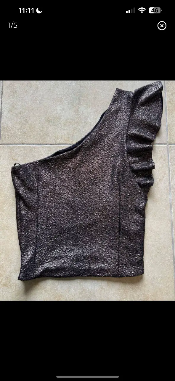 Top de un solo hombro con detalle de volado en el hombro. Confeccionado en tela brillante, ideal para una fiesta o salida.