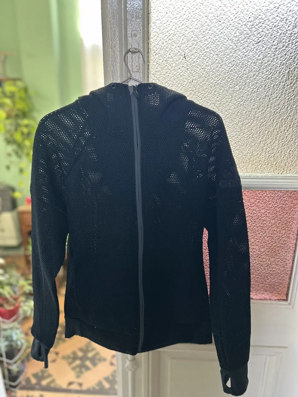 Buzo deportivo Adidas Original negro con cierre y capucha, ideal para entrenamientos. Diseño de malla transpirable y detalles de la marca.